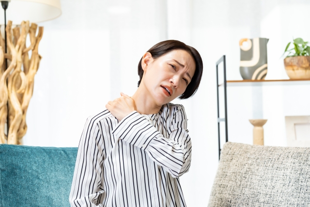 部屋で肩を押さえる女性